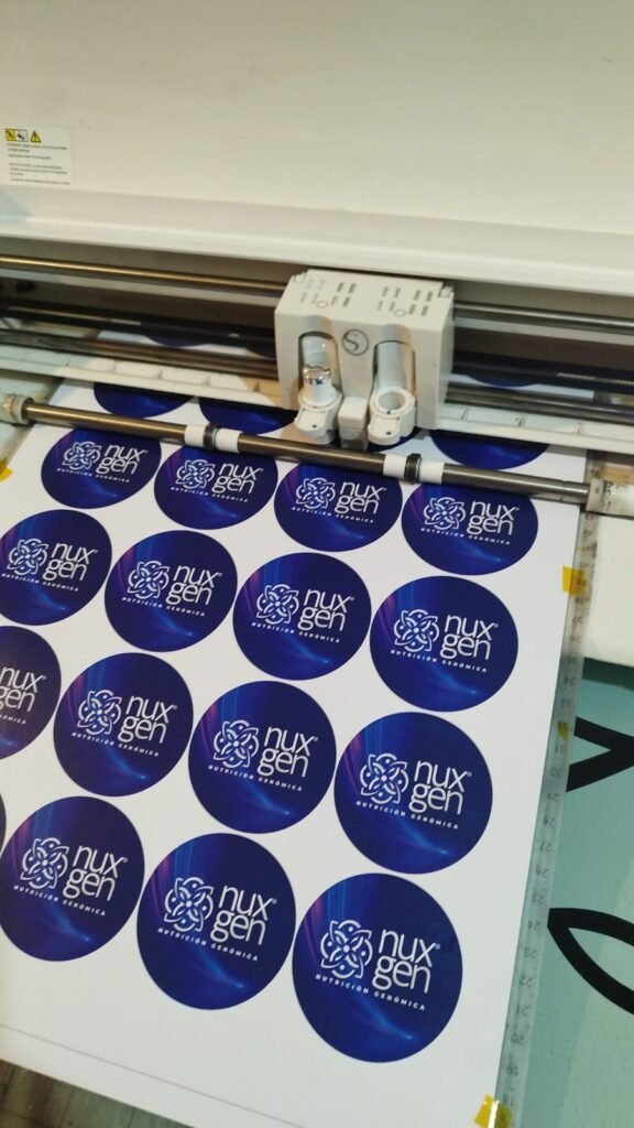 Hoja de diseños de botones publicitarios personalizados siendo cortada en el plóter
