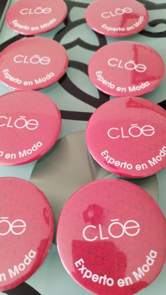 Botones publicitarios personalizados en rosa para la marca Cloé con la leyenda Experto en Moda